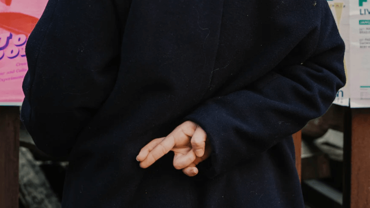 A person crossing their fingers behind their back.