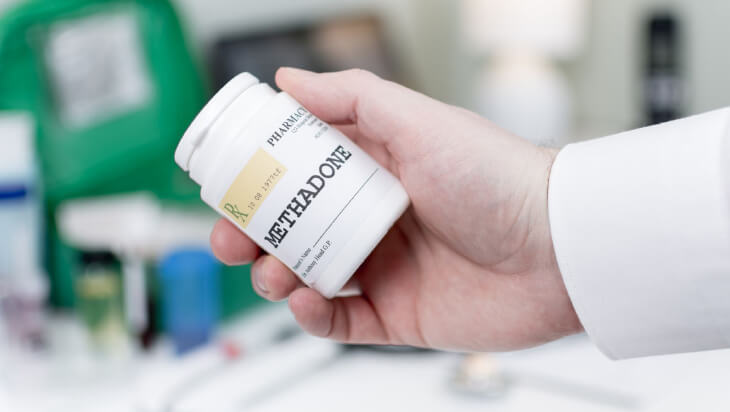 A person holding a bottle of methadone medication.