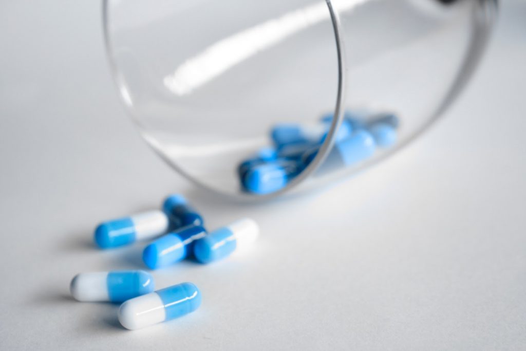 Close up of prescription pills spilled out of a glass