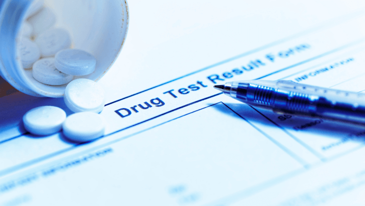 a bottle of opioids spill out over a drug test result form