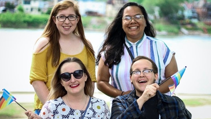 Four friends holding Pride flags