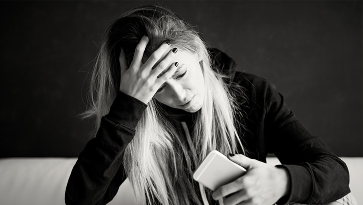 An upset woman who is on a waitlist checks her phone