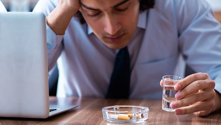 Male employee holding a glass of alcohol in the office