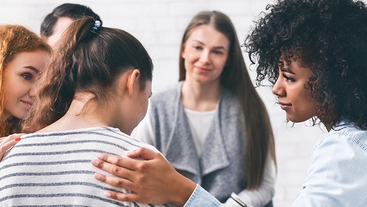 A group therapy session with women showing their support to another individual