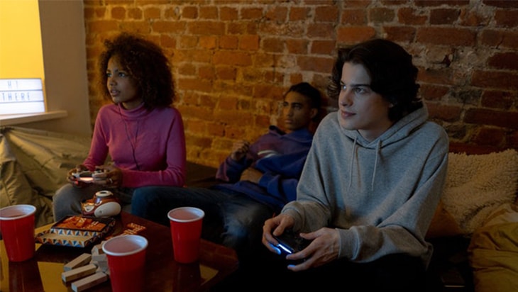 Teenagers playing video games while drinking