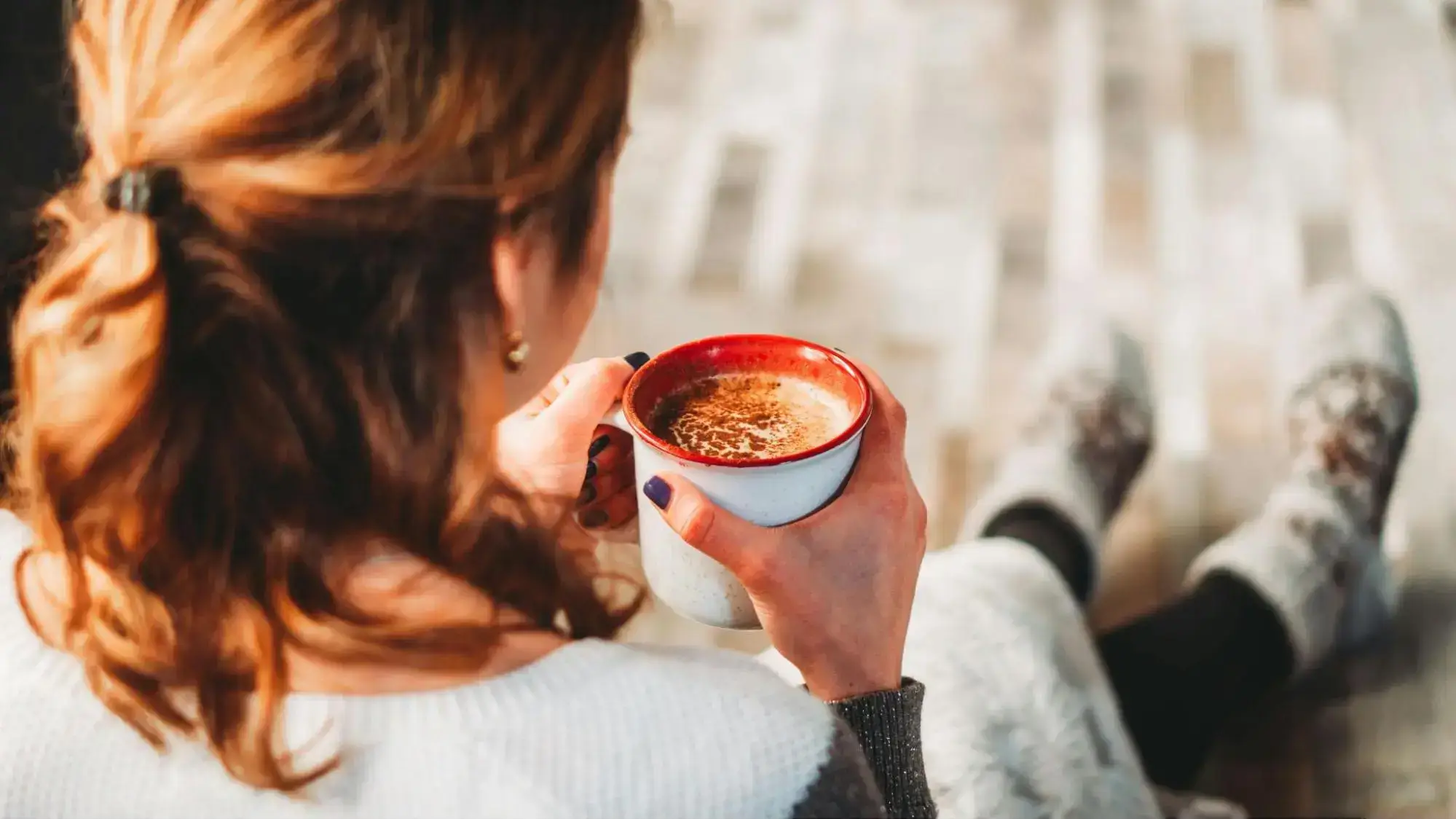 A woman drinking hot cocoa on a couch looking relaxed