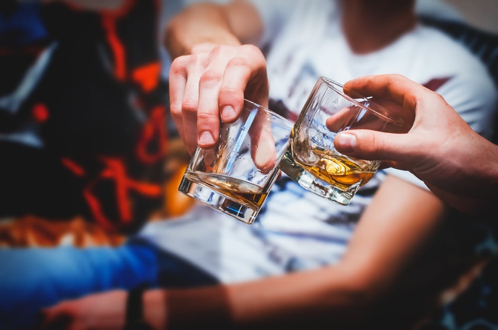 Two hands clinking glasses of whisky