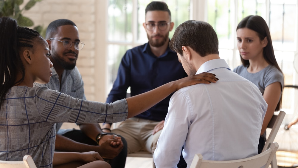 Man being comforted in a group counselling session