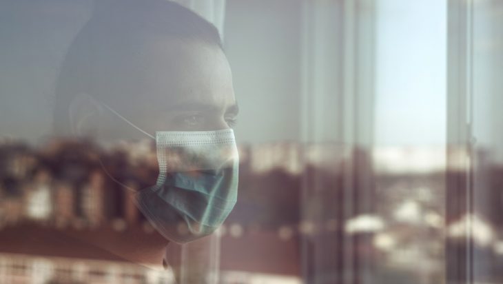 Man wearing mask looking out the window