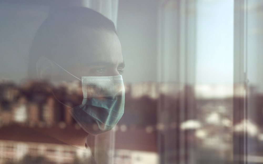 Man wearing mask looking out the window
