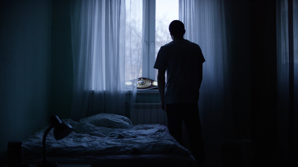 Sillhouette of a man standing alone near the window
