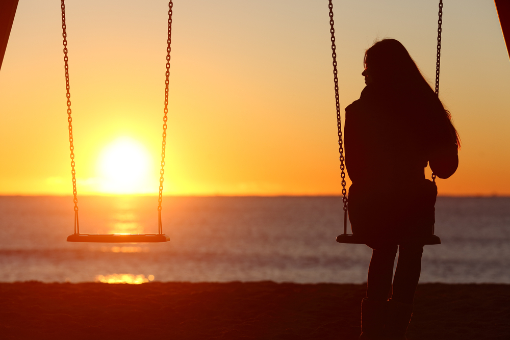 Young woman swinging alone on the beach