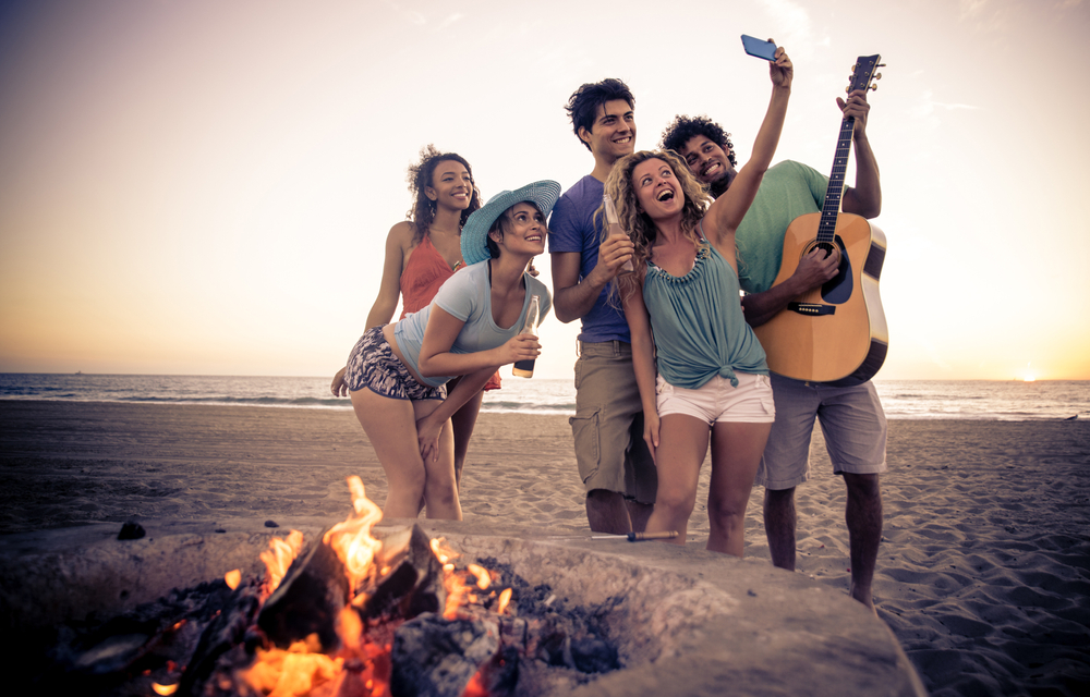 Group of happy friends taking photos at the beach.