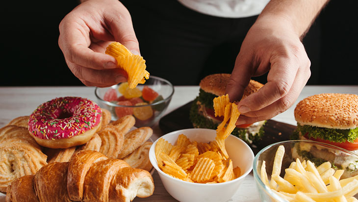 Hands getting chips from a table filled with food.