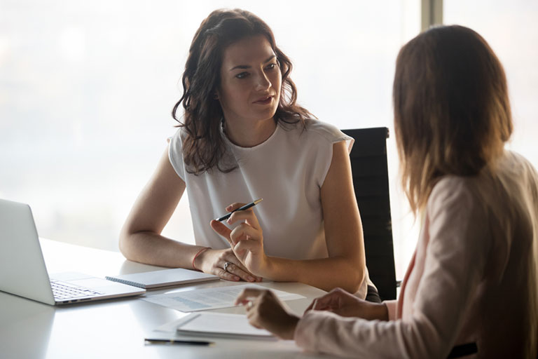 A female employee talking to her female boss about managing stress at work.