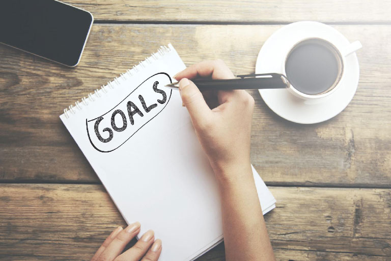 An overhead shot of someone writing addiction recovery goals in a notebook