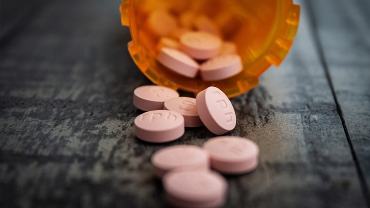 An open prescription drug bottle with pills spilling out