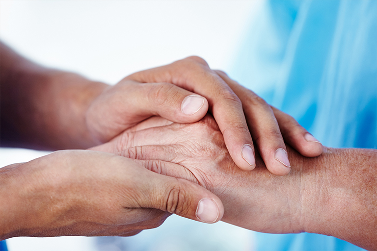 Two people holding each other’s hands to provide emotional support
