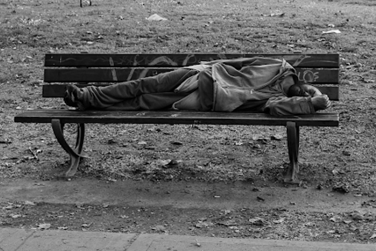 A drunk man sleeping on a bench at a park