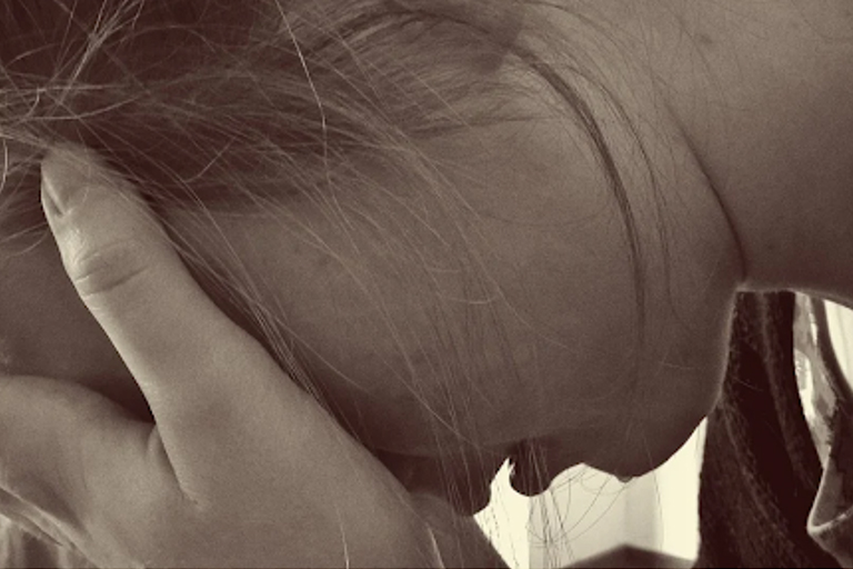 A woman suffering from depression, holding her face in her hands