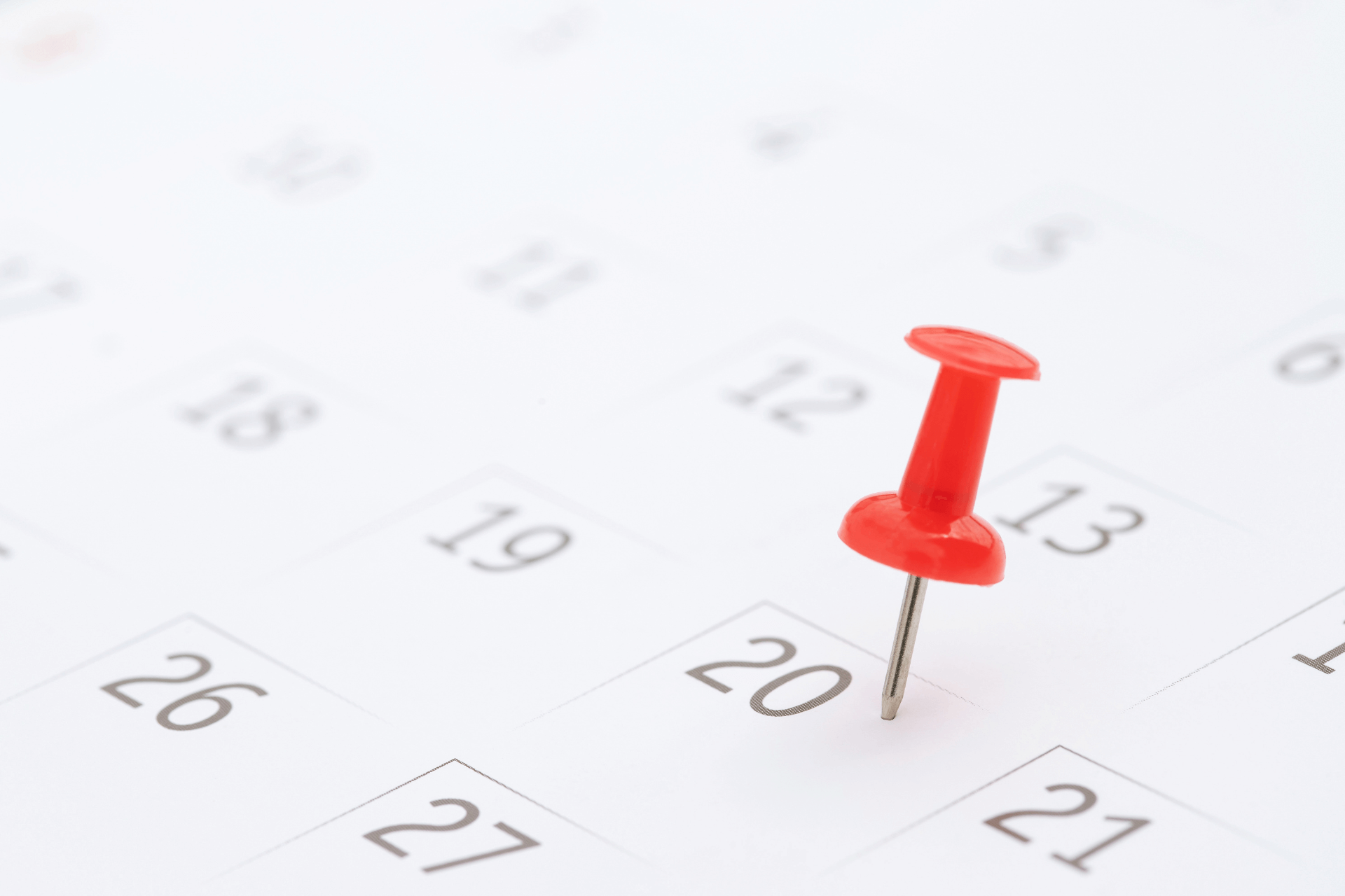 Close up of a calendar with a red pin on a date