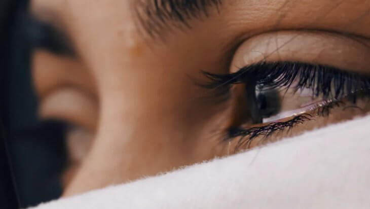 A teary-eyed person with half of their face covered