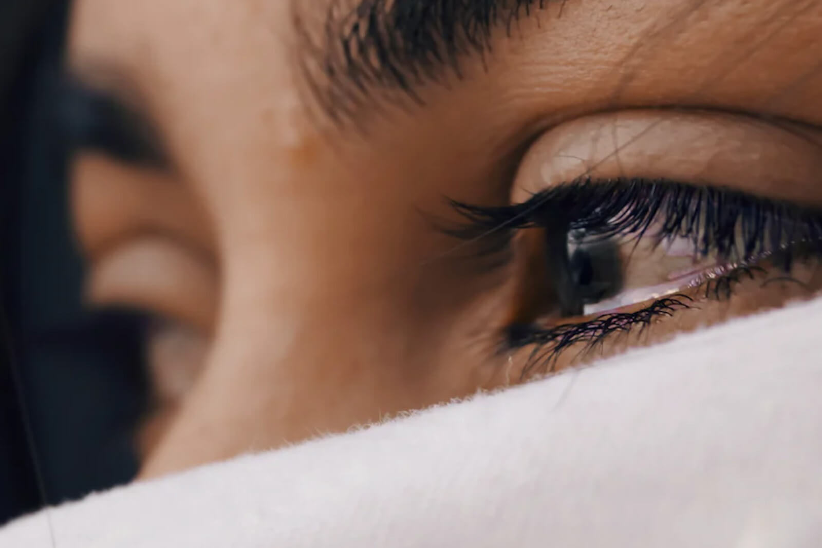 A teary-eyed person with half of their face covered