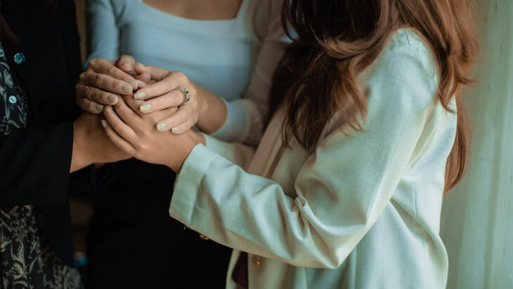 three women holding hands in comfort