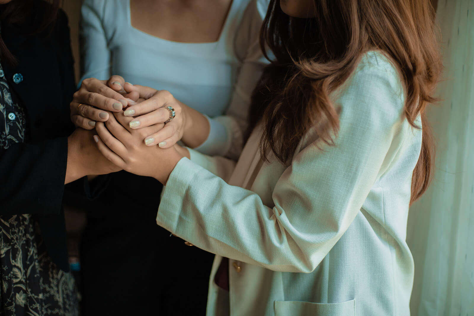 three women holding hands in comfort