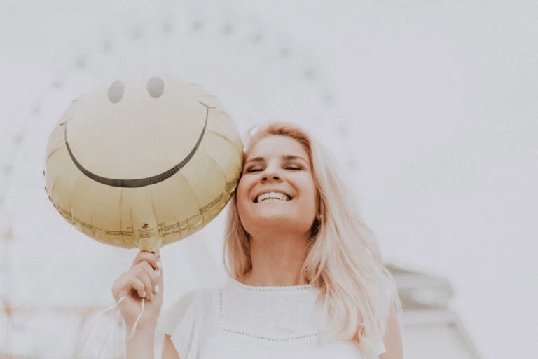 A smiling person holding a balloon