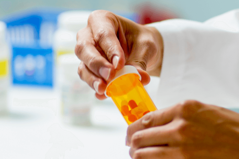 a pharmacist putting the lid on a prescription bottle