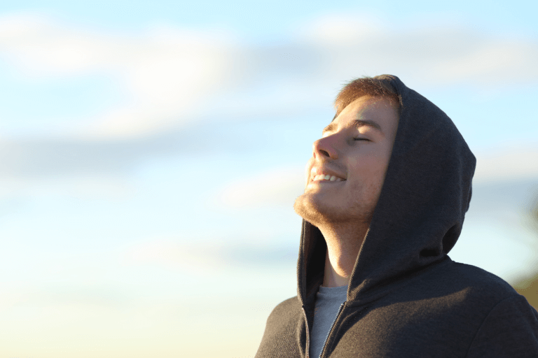  a man smiling at the the sun with their eyes closed 