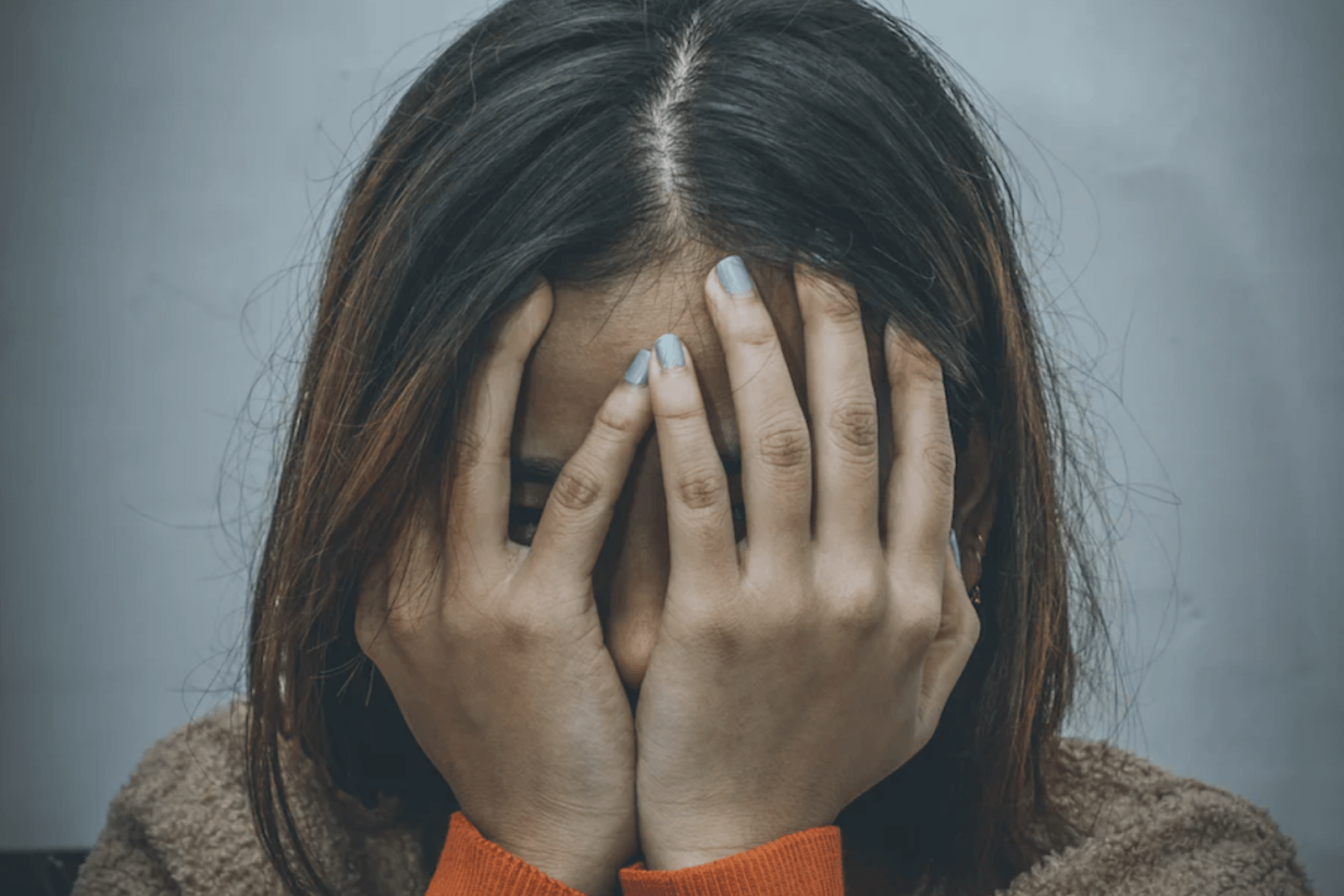 A young woman covering her face with her hands.