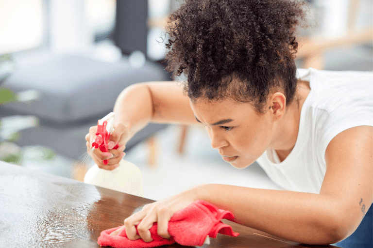 A woman cleaning a table thoroughly.