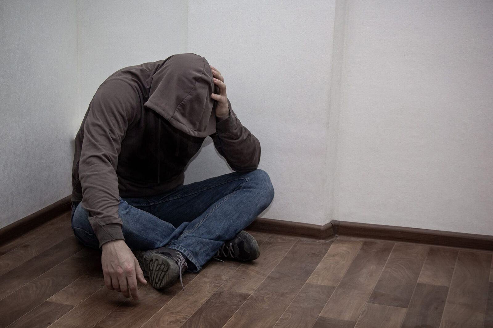 A person sitting in a corner with their head hung low