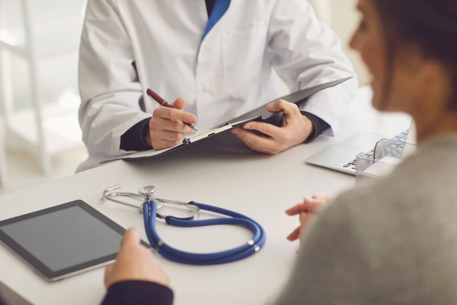 A medical professional takes notes during a consultation for opioid addiction treatment