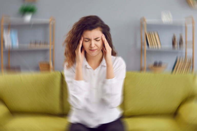 a woman pressing her fingers to her temples in a spinning room