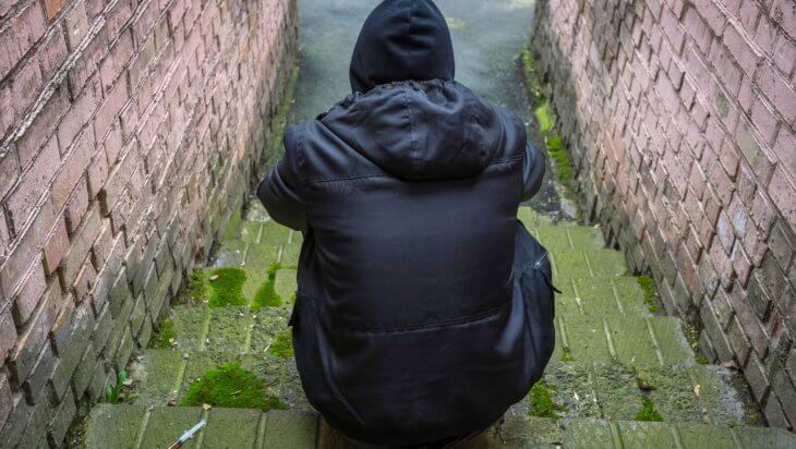 A man sitting on stone steps with a syringe beside him