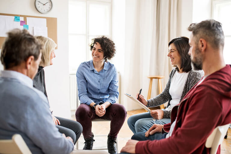 A group of people sitting and talking in chairs in a circle