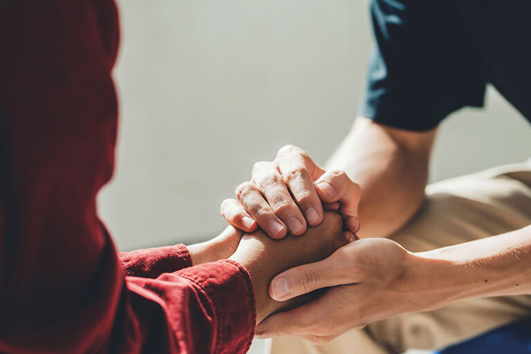 A person holding someone else’s hands in theirs as a show of support.