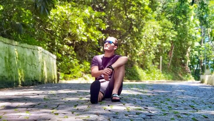 A man sitting on a cobblestone path looking up at the trees