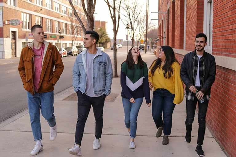 A group of five adults walking down a street together and laughing