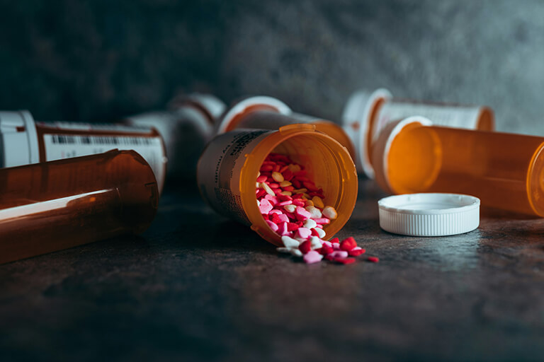 A few pill bottles on their side with one spilling pills

