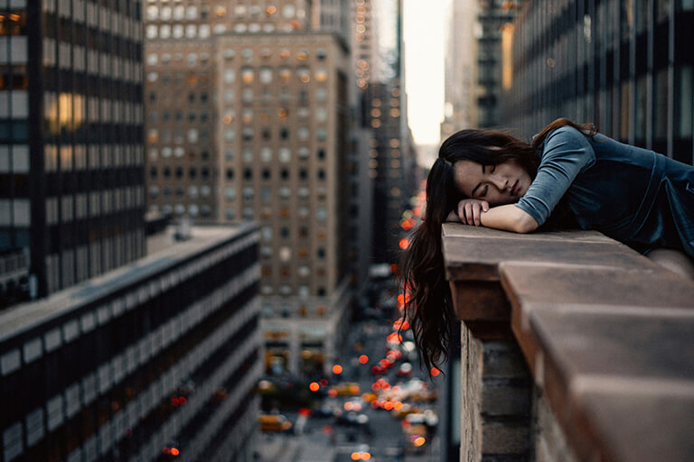A woman leaning on a brick railing overlooking a busy street