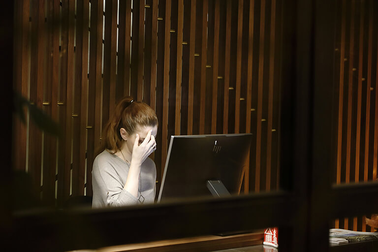 A woman with her head in her hand in front of a desktop monitor