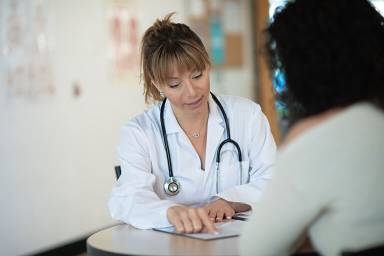 A doctor wearing a lab coat consults with a patient
