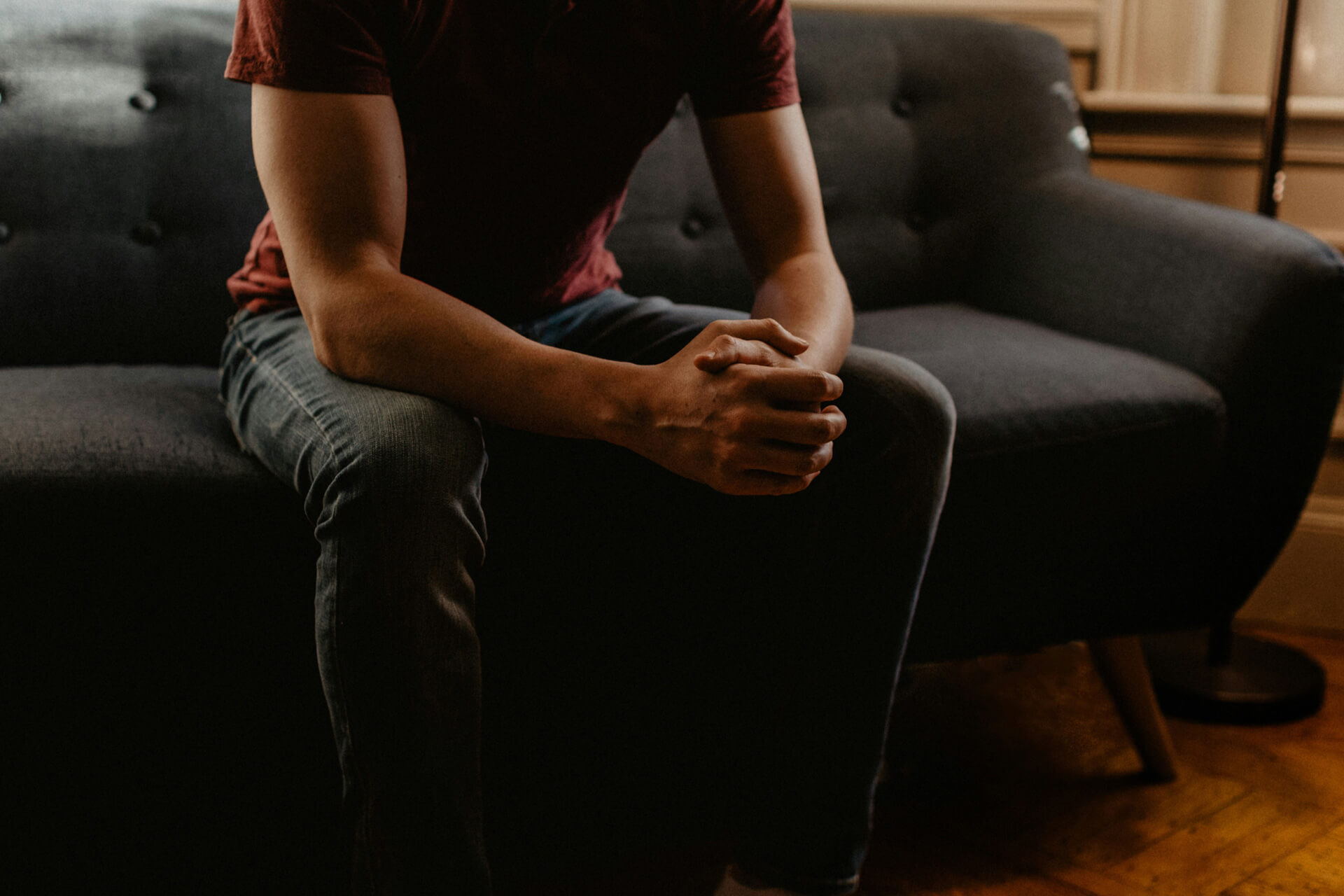 A man sitting on a couch with his hands clasped