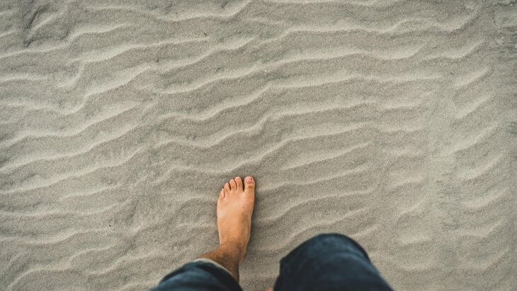 A man walking in bare feet on the sand