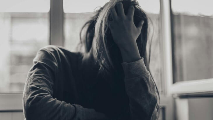 A woman with her head in her hand and her hair covering her face