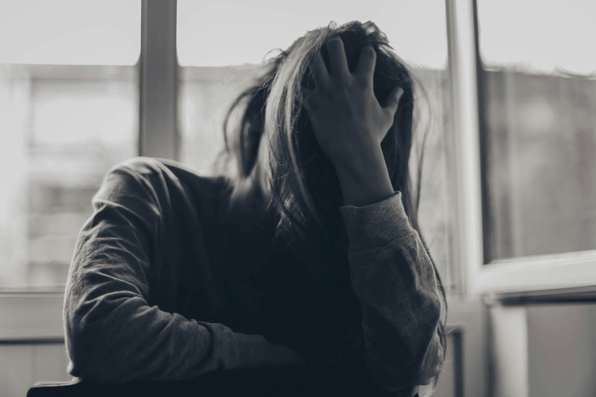 A woman with her head in her hand and her hair covering her face